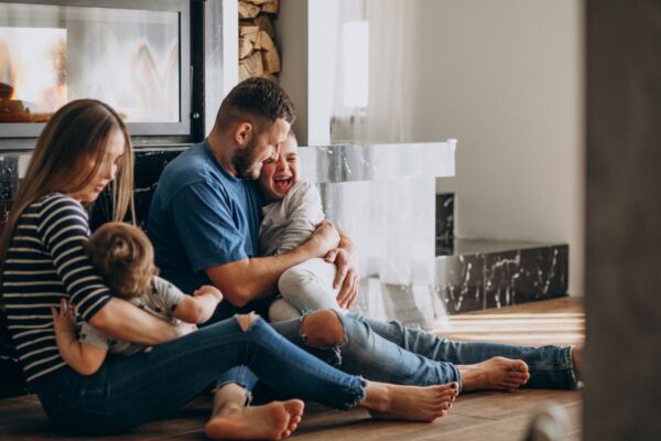 Familie fericită jucându-se lângă șemineu acasă